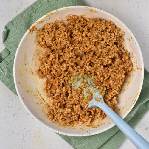 Stirred Healthy Puffed Rice Bar base in a mixing bowl with a silicone spatula.