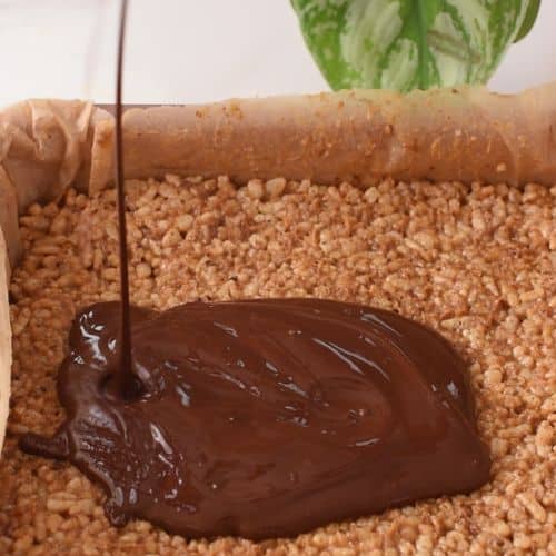 Pouring melted chocolate on the Healthy Puffed Rice Bar mixture.