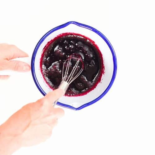 Stirring beetroot latte base in a saucepan.