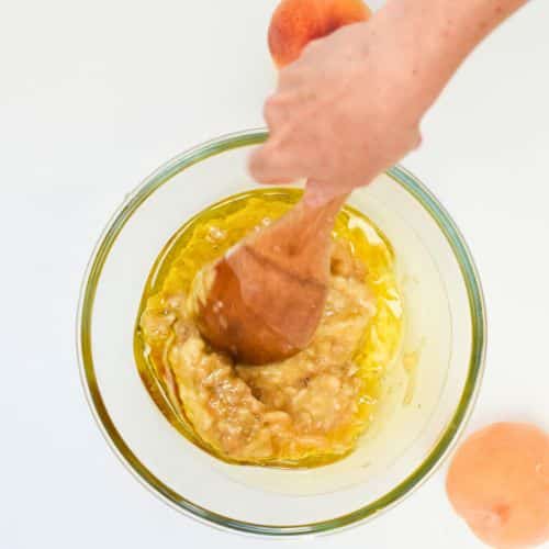 Mixing wet Vegan Peach Muffins ingredients in a bowl.