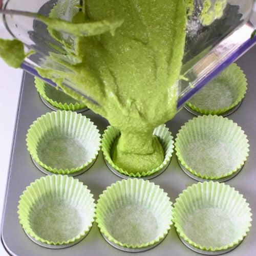 Pouring Vegan Spinach Muffin batter into mini-muffin cups.