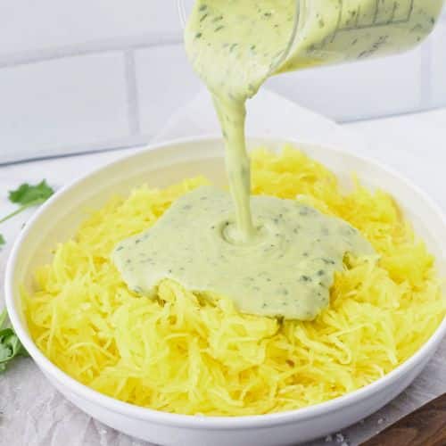 Pouring Alfredo sauce on the Vegan Spaghetti Squash Alfredo