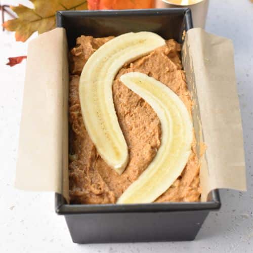 Pumpkin Banana Bread batter in a pan with a sliced banana on the top.