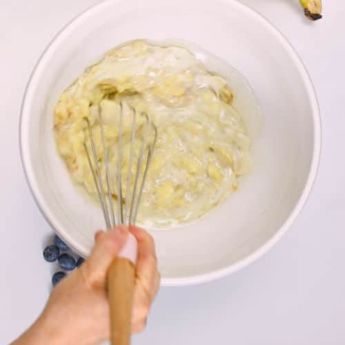 Stirring bananas and milk for the Vegan Banana Blueberry Muffins