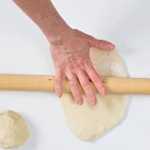 Flattening Vegan Naan Bread with a rolling pin.