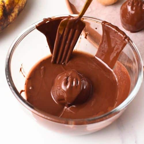 Dipping Banana Peanut Butter Balls into melted chocolate.