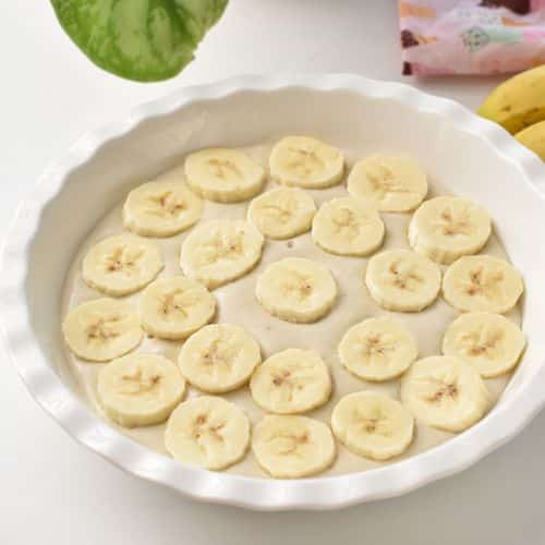 Adding banana slices to the pudding base.