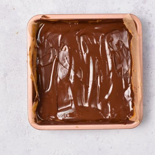 Melted chocolate on top of the No Bake Twix Bars in the pan.