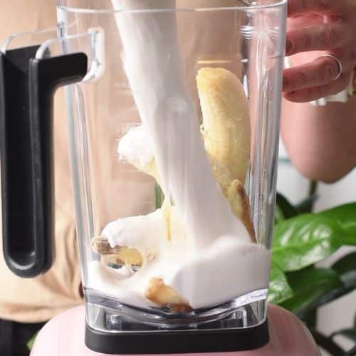 Pouring Peanut Butter Banana Milkshake into a blender.