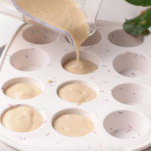 Pouring the Peanut Butter Banana Milkshake into a silicone muffin pan.