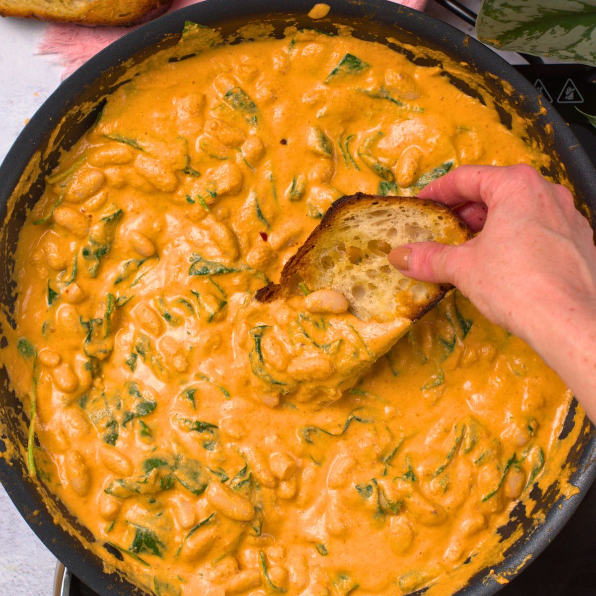 Digging a slice of bread in Creamy Butter Beans.