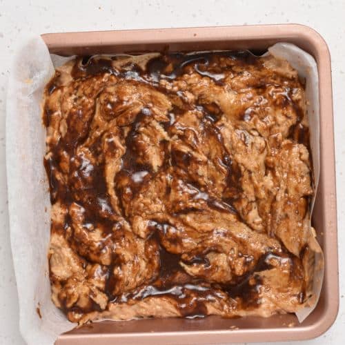 Applesauce cake with an applesauce swirl in a baking pan.