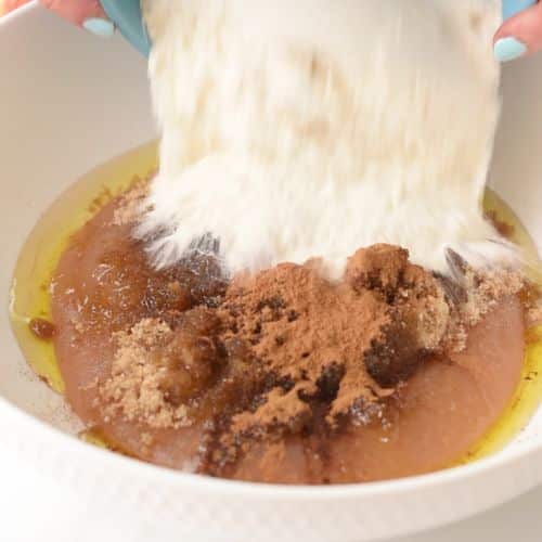 Pouring flour into a bowl to make the applesauce cake batter.