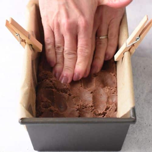 Pressing Brownie Protein Bars in a loaf pan.