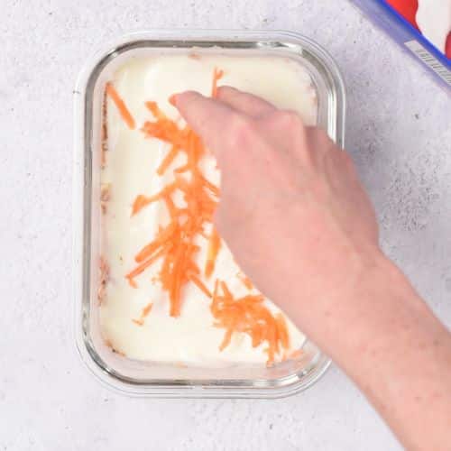 Adding grated carrots on top of the Carrot Cake Overnight Weetbix.