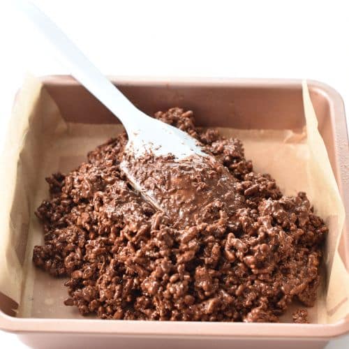 Spreading Chocolate Rice Bubble Slice into a pan.