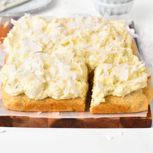 Easy Coconut Cake sliced on a chopping board.