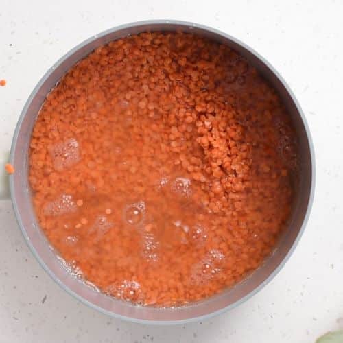 Lentil cooking in water in a saucepan.