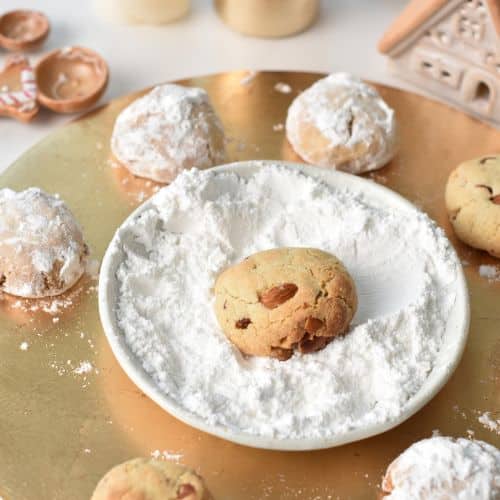 Rolling warm Almond Snowball Cookies in powdered sugar.