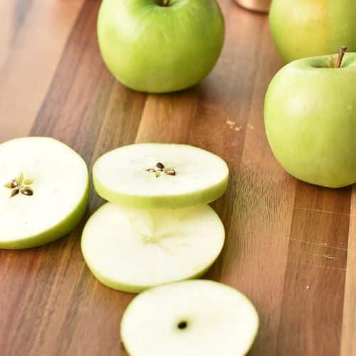 Slice of green apples on a chopping board.