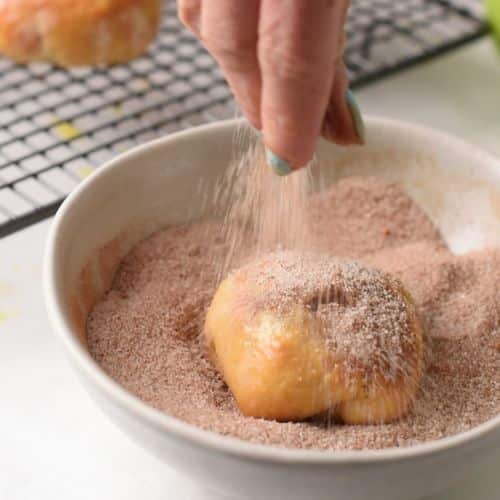 Rolling Baked Apple Donuts in cinnamon sugar.