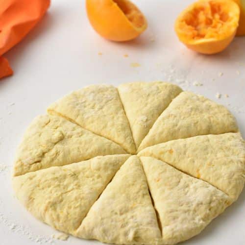 Orange Scones dough disc cut into 8 triangles.