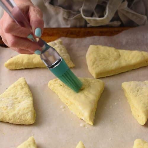 Brushing Orange Scones with plant-based milk.