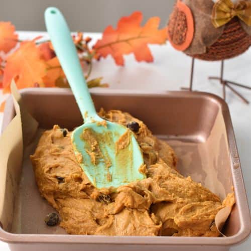 Pouring Pumpkin Blondie batter in a square pan.