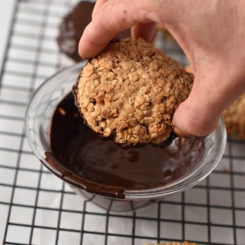 Dipping 3-Ingredient Oatmeal Cookies into melted chocolate.