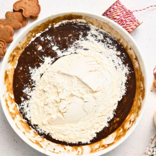 Adding flour to the Gingerbread Banana Bread mixture in a bowl.