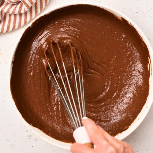 Stirring Gluten-Free Chocolate Muffin batter in a bowl with a whisk.