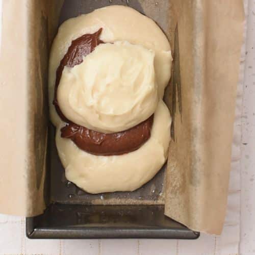 Three dollops of alternating Marble Pound Cake batter in a loaf pan.