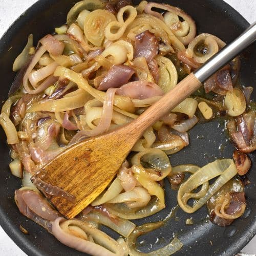 Red and white onions in a frying pan.