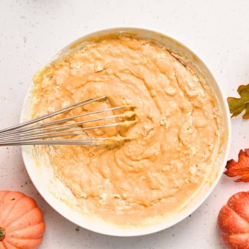 Incorporating flour into Pumpkin Crepes ingredients in a bowl.