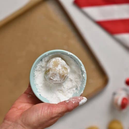 Rolling the Almond Cookie dough ball in powdered sugar.