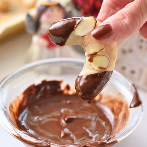 Dipping Almond Horns Cookies into melted chocolate.