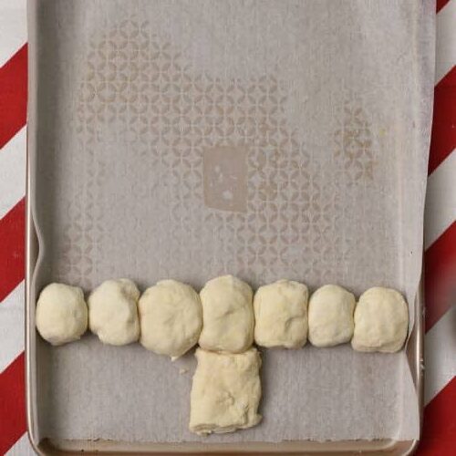 Adding dough balls to form the Pull Apart Christmas Tree on a baking sheet.