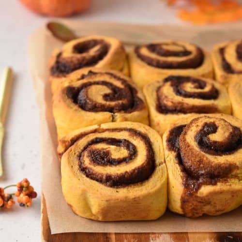 Sweet Potato Cinnamon Rolls colling down on a wooden board.