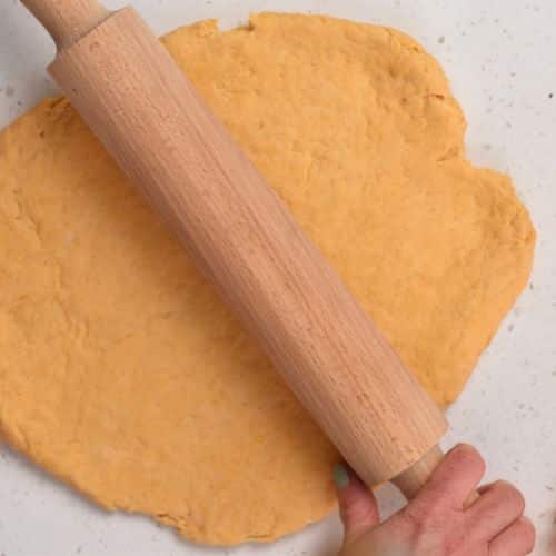 Flattening the Sweet Potato Cinnamon Roll dough with a rolling pin.