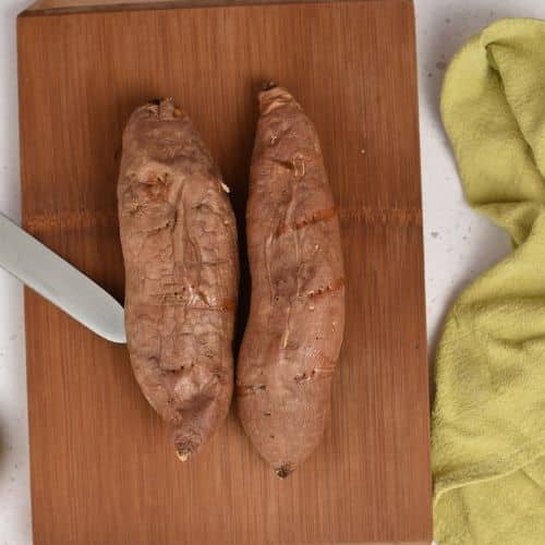 Pricked sweet potatoes on a chopping board.