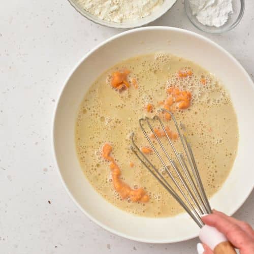 Whisking wet Sweet Potato Pancake ingredients in a mixing bowl.