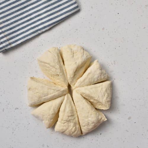 Cutting 3-Ingredient Dinner Roll dough into 8 parts.