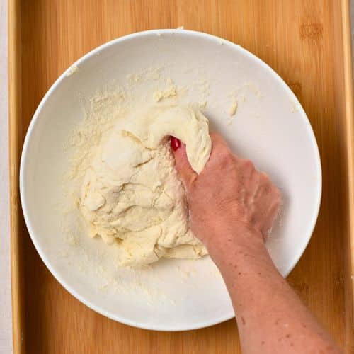 Kneading the 2-Ingredient Pizza Dough in a bowl.