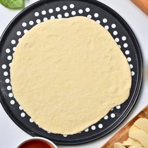 2-Ingredient Pizza Dough rolled and placed on a pizza pan.