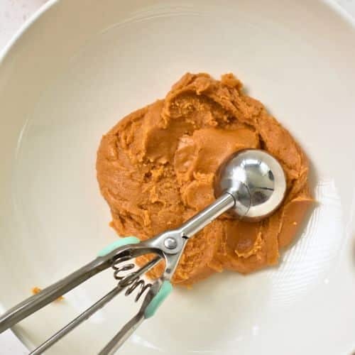 Scooping 3-Ingredient Peanut Butter Cookie dough with a cookie scoop.