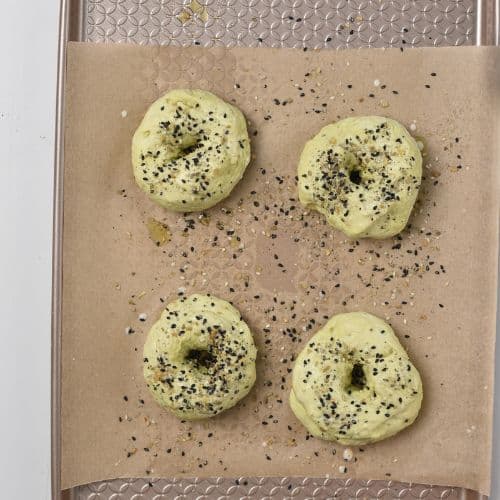 Avocado Bagels ready to bake on a baking sheet.