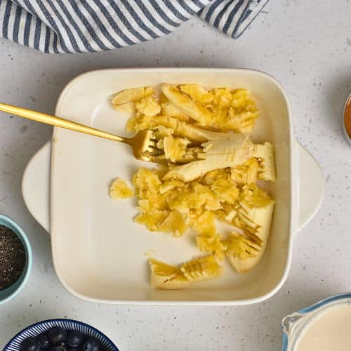 Mashing banana in a square pan.