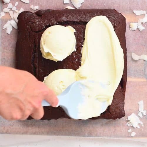 Spreading coconut cream frosting on the coconut chocolate cake.