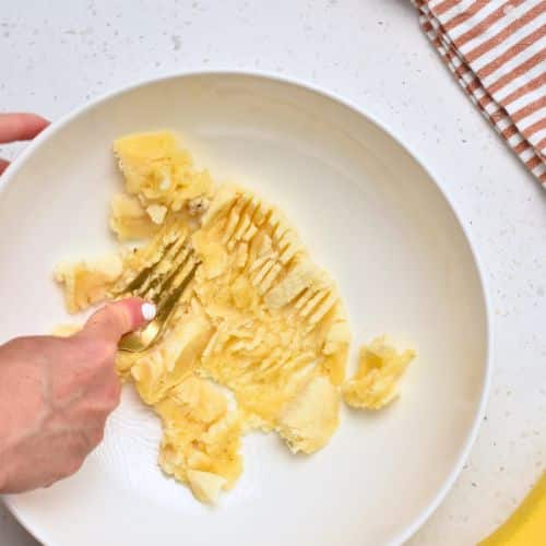 Mashing bananas in a mixing bowl.