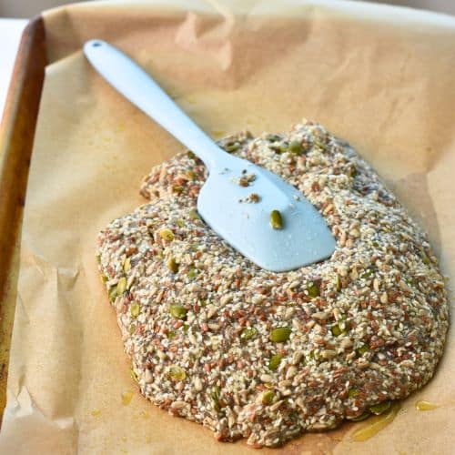 Spreading the Seed Cracker dough on a baking sheet.